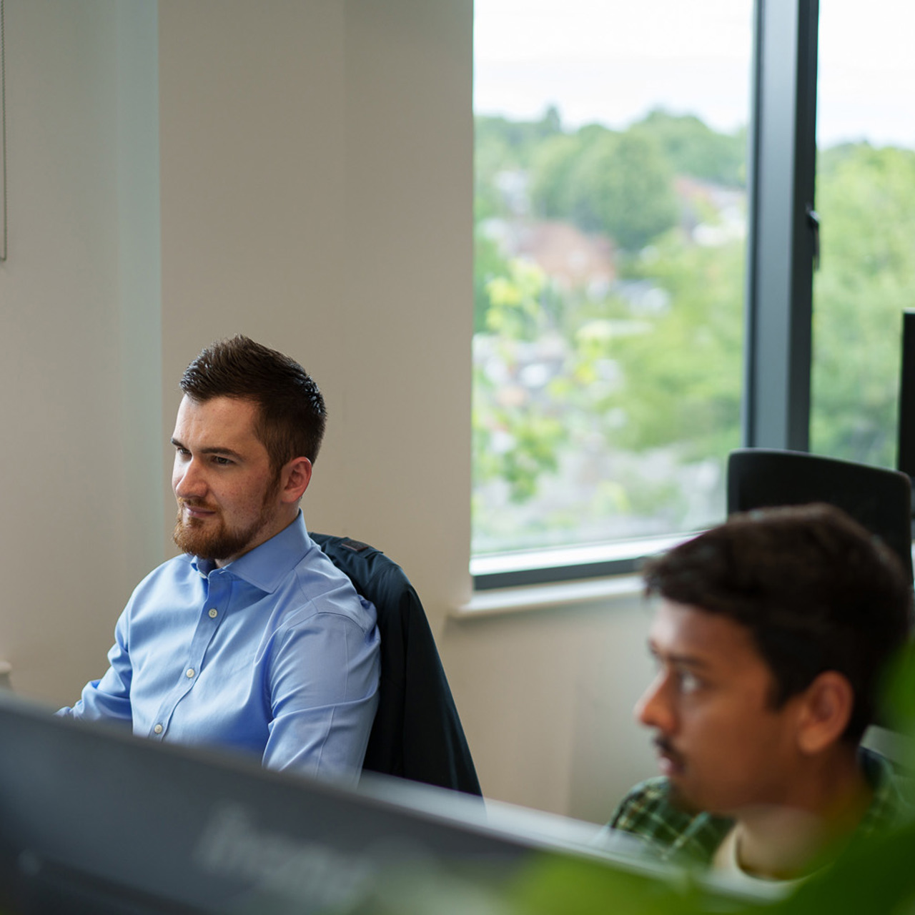 Two colleeagues sitting at desks looking at computer screens